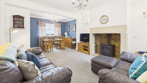 A living room with leather sofas, a dining area with wooden furniture, a fireplace, and a television.
