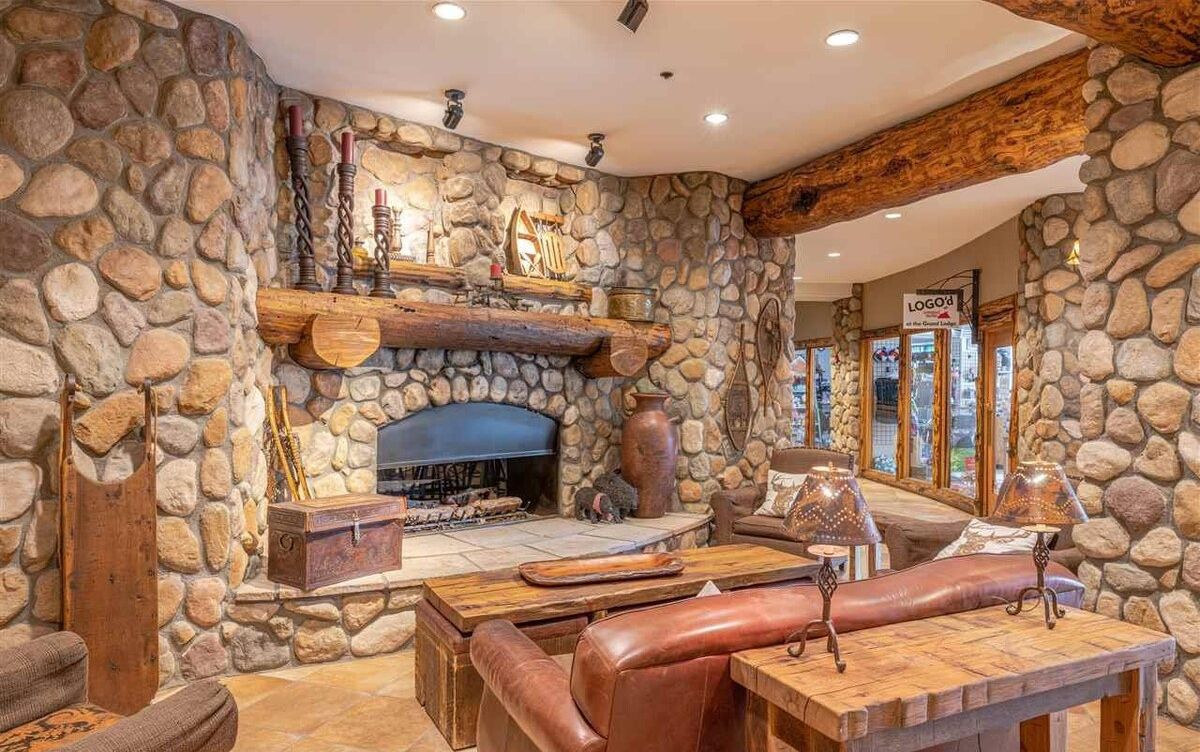 A stone-walled room with a fireplace, leather seating, and a wooden table.
