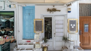 A storefront with a blue door, a sign above the door, and various items displayed outside.