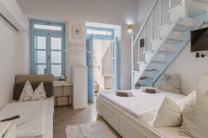 A bedroom with a bed, a desk, a chair, a TV, and a staircase.