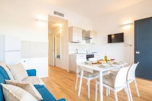 Un appartement moderne doté d’un coin repas, d’une kitchenette et d’un téléviseur fixé au mur.