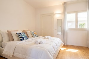 A bedroom with a bed, pillows, a mirror, and a window.