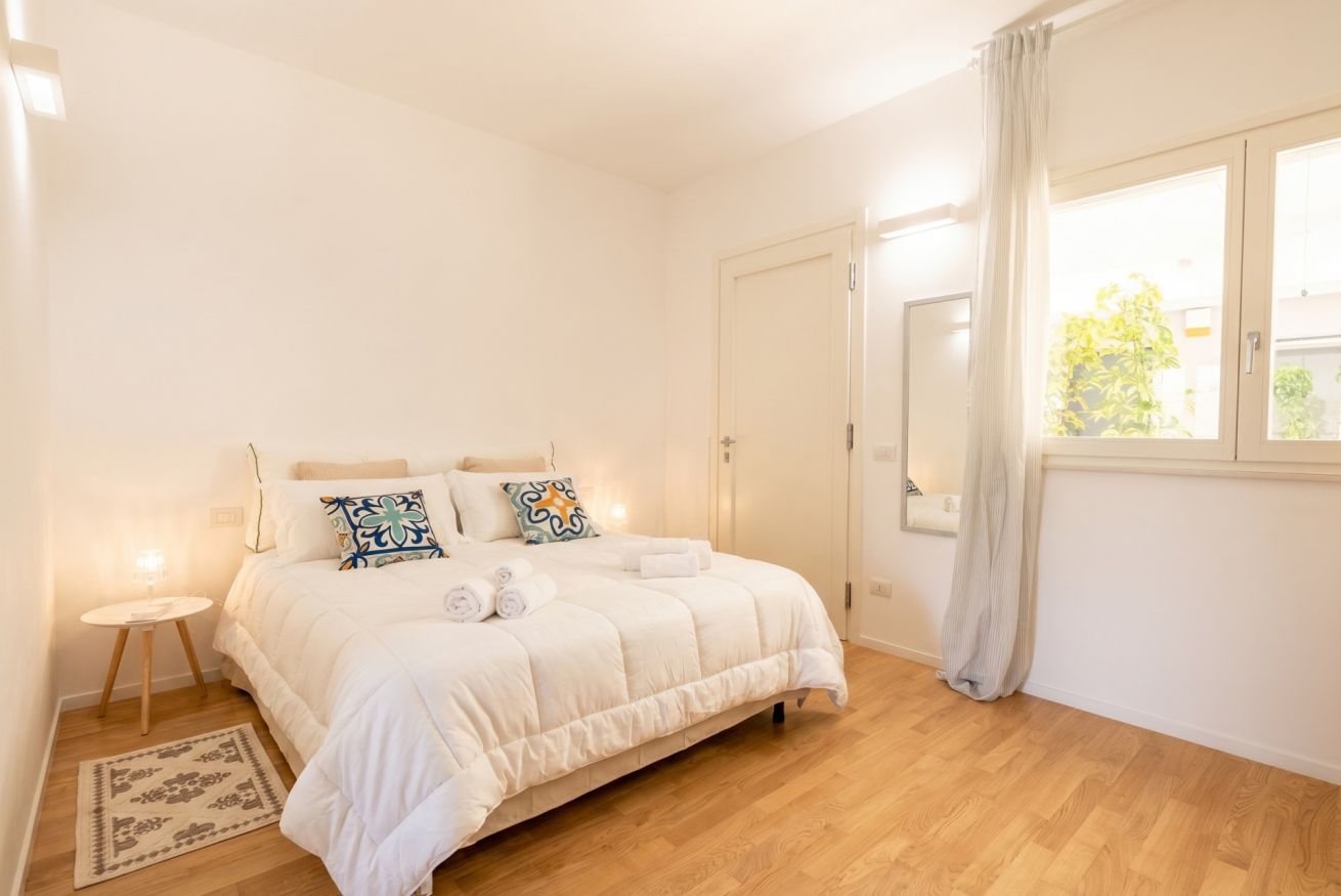 A bedroom with a bed, bedside table, and a window with curtains.