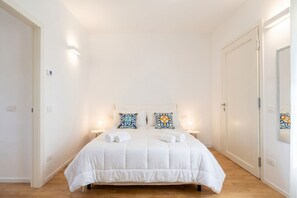 Een slaapkamer met een groot bed, twee nachtkastjes en een spiegel aan de muur.