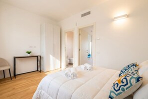 A bedroom with a bed, a desk, and a chair. There is a bathroom visible through an open door. - Maison Aurora+ Pivate Parking Space (Bari)