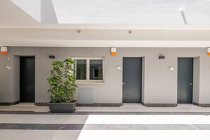 A modern building with a flat roof, large windows, and a potted plant in the center.