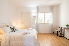 A bedroom with a bed, a chair, a desk, a window, and a door.
