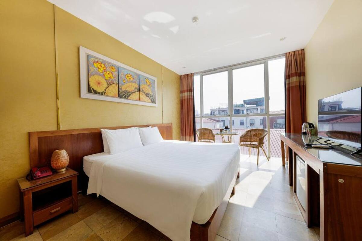 Une chambre d’hôtel avec un grand lit, un bureau, une chaise et une fenêtre donnant sur la ville.
