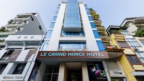 Das Le Grand Hanoi Hotel mit einem markanten Eingang, einer modernen Fassade und freiem Blick auf die umliegenden Gebäude.