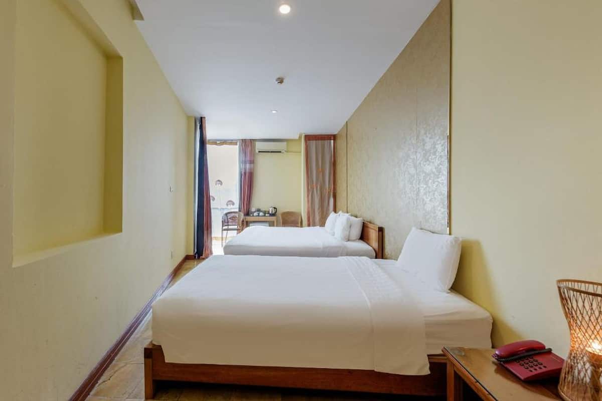 Une chambre d’hôtel avec deux lits, un bureau avec un téléphone et une chaise.