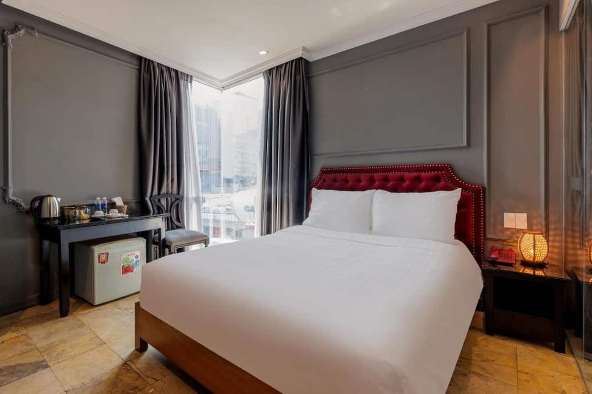 Une chambre d’hôtel avec un grand lit, un bureau avec une bouilloire, un petit réfrigérateur et une vue sur la ville.