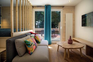 A modern living room with a sofa, colorful cushions, a wooden table with a vase, and a large window with curtains. - Large studio with terrace (Vannes)