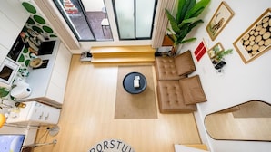 Un salon moderne avec un plancher en bois, un canapé, une table basse et une grande fenêtre.