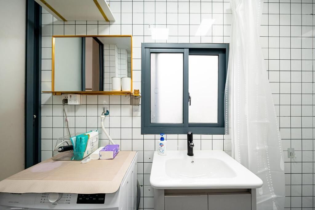 A bathroom with a white sink, a mirror with a wooden frame, and a window with a blue frame.