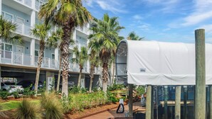 Ein Hotel mit überdachter Außenbestuhlung, Palmen und einem Pool.