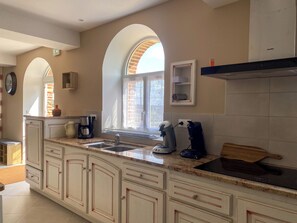 A kitchen with a large island, a window with a view, and a coffee maker.