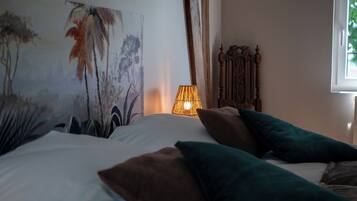 A bedroom with a bed, pillows, a lamp, and a painting on the wall.