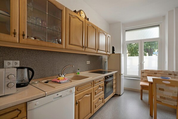Una cocina con armarios de madera, lavavajillas, estufa y ventana con vistas.