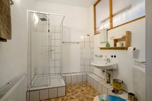 Un baño con ducha, lavamanos y piso de baldosas.