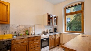 Una cocina con armarios de madera, una estufa, un fregadero y una ventana con vistas a árboles.