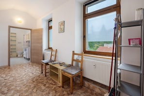 Een kamer met een houten stoel, een kleine tafel, een radiator, een raam met uitzicht en een plank met een boek.