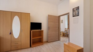 Een kamer met een televisie, een houten garderobe en een bureau.