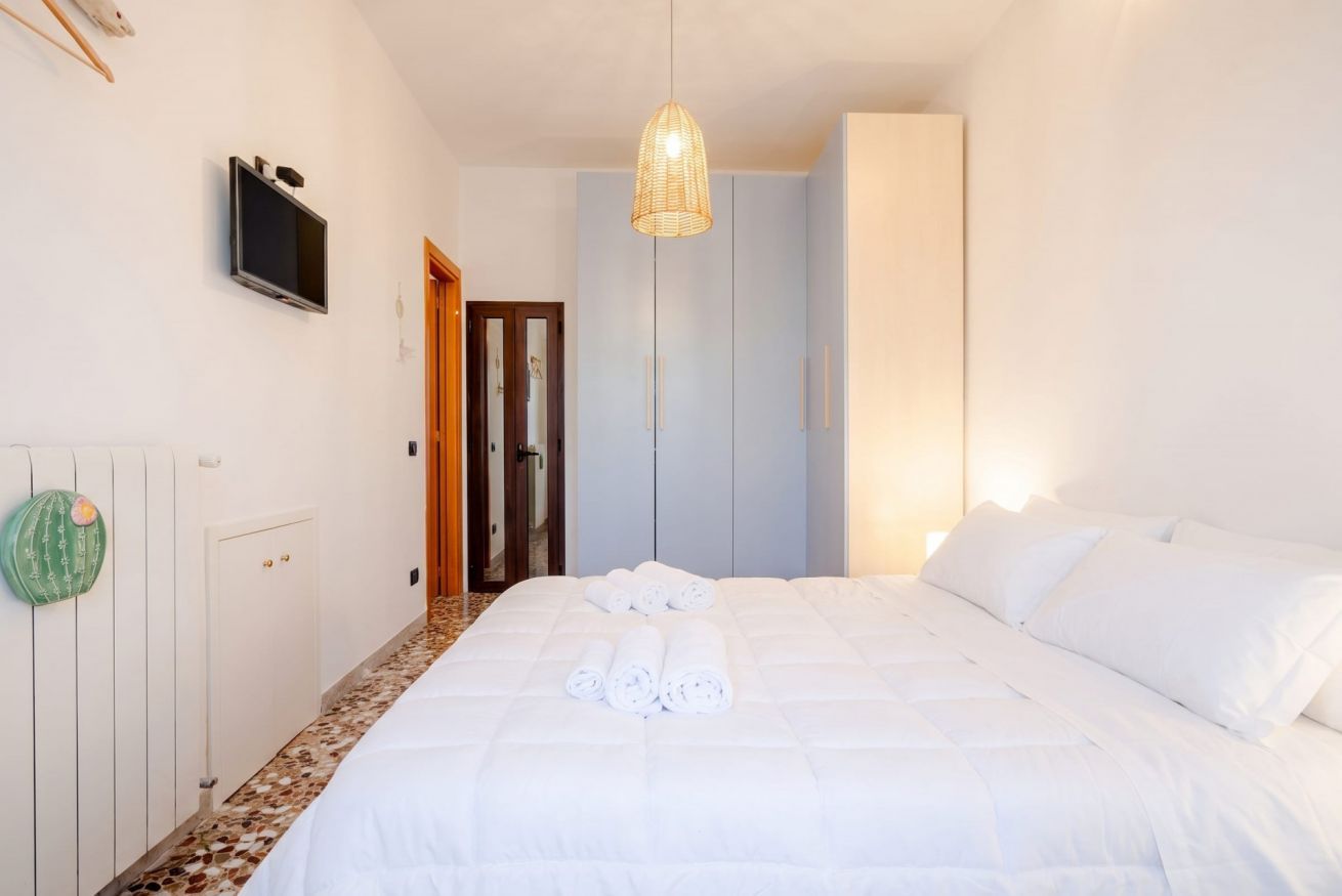 A bedroom with a bed, a television on the wall, and a door leading to another room.