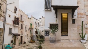 A narrow street with buildings on either side, a cobblestone path, and a door with a number 7 sign. - Mare Tra i Tetti -  The sea among the rooftops (Monopoli)