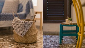 A cozy room with a woven basket on the floor, a teal chair with a small table beside it, and a window with blinds. - Mare Tra i Tetti -  The sea among the rooftops (Monopoli)
