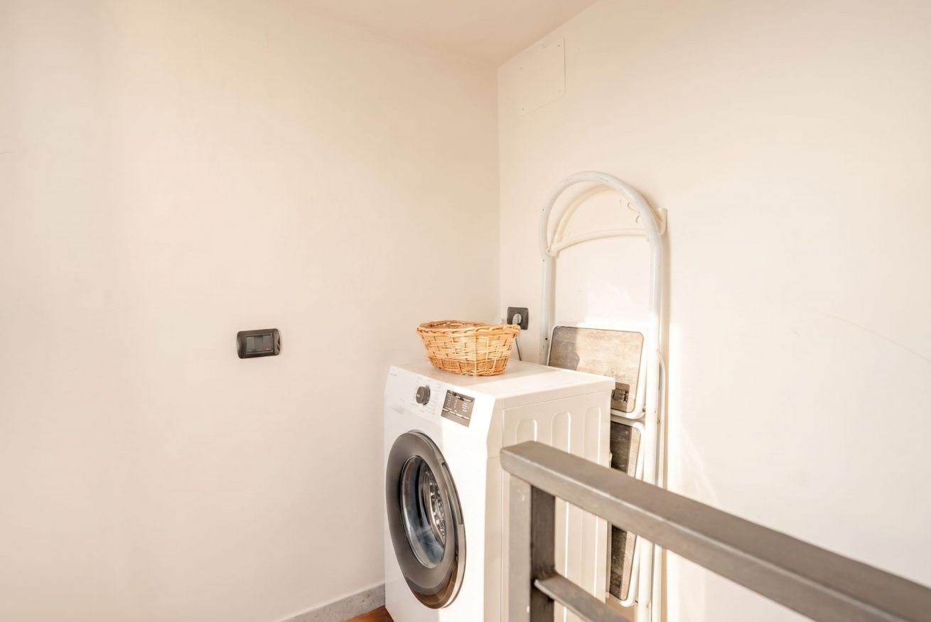 A laundry room with a washing machine, a basket on top, and a metal railing.