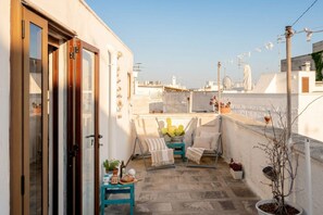 Une terrasse sur le toit, aménagée avec un espace salon, des plantes en pot et offrant une vue sur le paysage urbain.