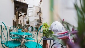 A narrow street with a small outdoor seating area featuring a turquoise metal table and chairs. - Mare Tra i Tetti -  The sea among the rooftops (Monopoli)