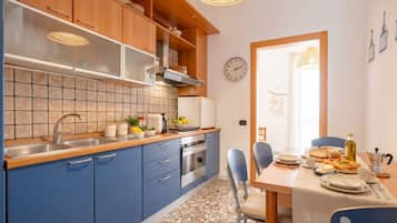 Une cuisine moderne avec des meubles bleus, un pare-feu en carreaux et un coin repas avec une table mise pour deux personnes.