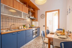 Une cuisine moderne avec des meubles bleus, un pare-feu en carreaux et un coin repas avec une table mise pour deux personnes.