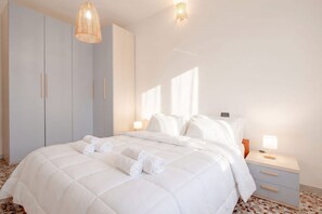 Un dormitorio con cama, mesitas de noche y un armario.