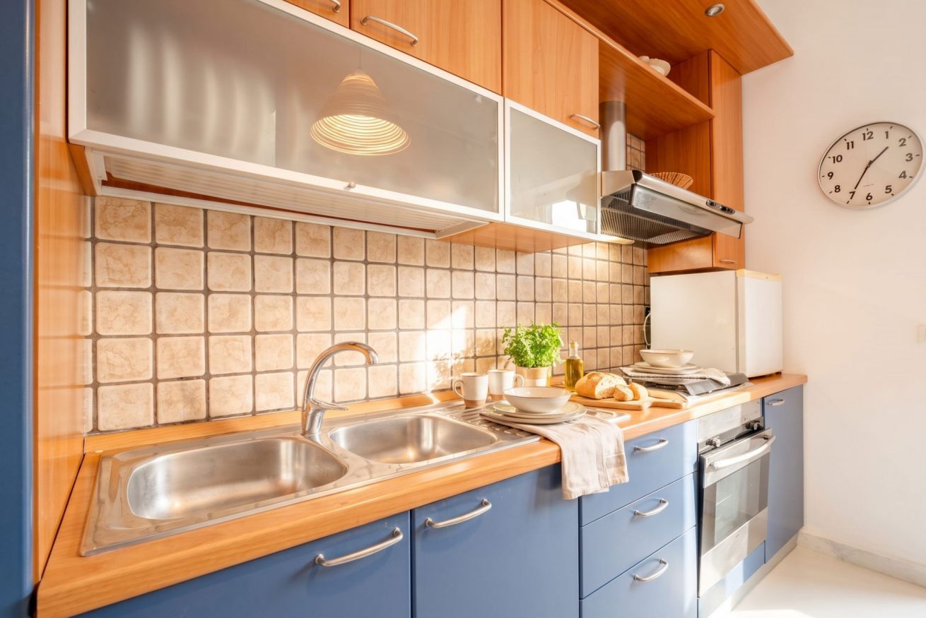 Una cocina con un lavaplatos doble, una estufa y un reloj en la pared.