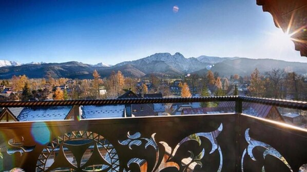 Ein Balkon mit Blick auf eine Berglandschaft und ein Dorf darunter.