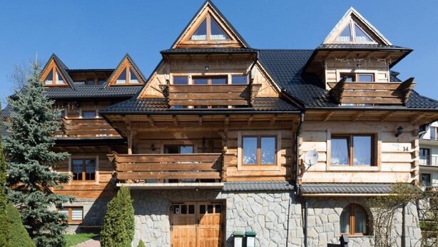 Een ruime houten chalets met meerdere verdiepingen, een stenen fundering en een groot balkon.