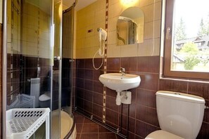 Ein Badezimmer mit Duschkabine aus Glas, einem weißen Waschbecken und einer Toilette.