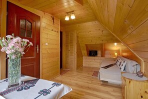 Eine Holzhütte mit gemütlicher Einrichtung, mit Essbereich, Tisch und Stühlen, einer Couch und einem Kamin.