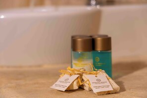 Two bottles of bath products and two small packages tied with yellow strings, placed on a bathroom counter. - Majestic Manor Otel (Mardin)