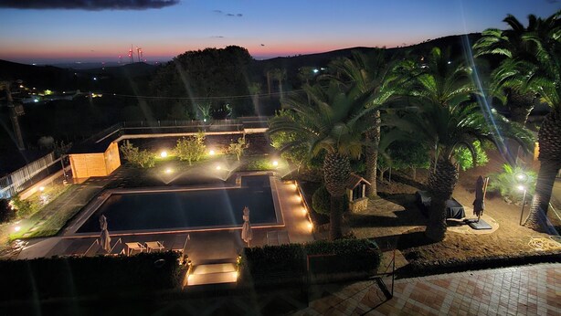 A nighttime view of a resort with a pool, palm trees, and a well-lit walkway.