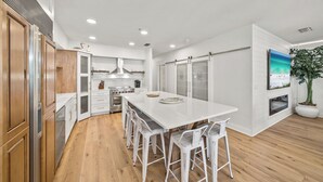 Una cocina moderna con armarios blancos, una isla central y taburetes de bar.
