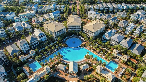 Vista aérea de una zona residencial con varias casas, una piscina central y abundante vegetación.