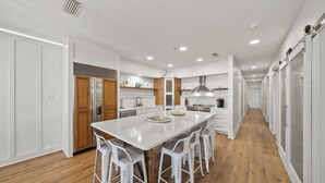 Una cocina moderna con una isla central, armarios blancos y suelo de madera.