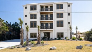 Um edifício residencial de vários andares com telhado plano, várias varandas e uma entrada frontal.