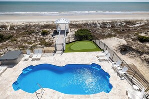 A pool area with a view of the beach, a gazebo, and a putting green. - Casa Blanco: Oceanfront House - 10 BR 11.5 BA (Emerald Isle)