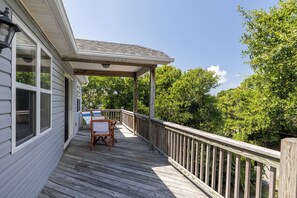 Una terrassa de fusta amb barana, zona coberta i taula amb cadires.