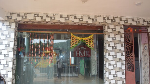 Entrada de hotel con fachada de baldosas, puerta de cristal y un letrero con las iniciales 'HMT'.