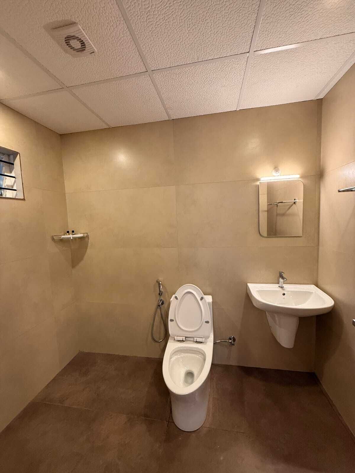 Et lille, rent badeværelse med toilet, håndvask og spejl.